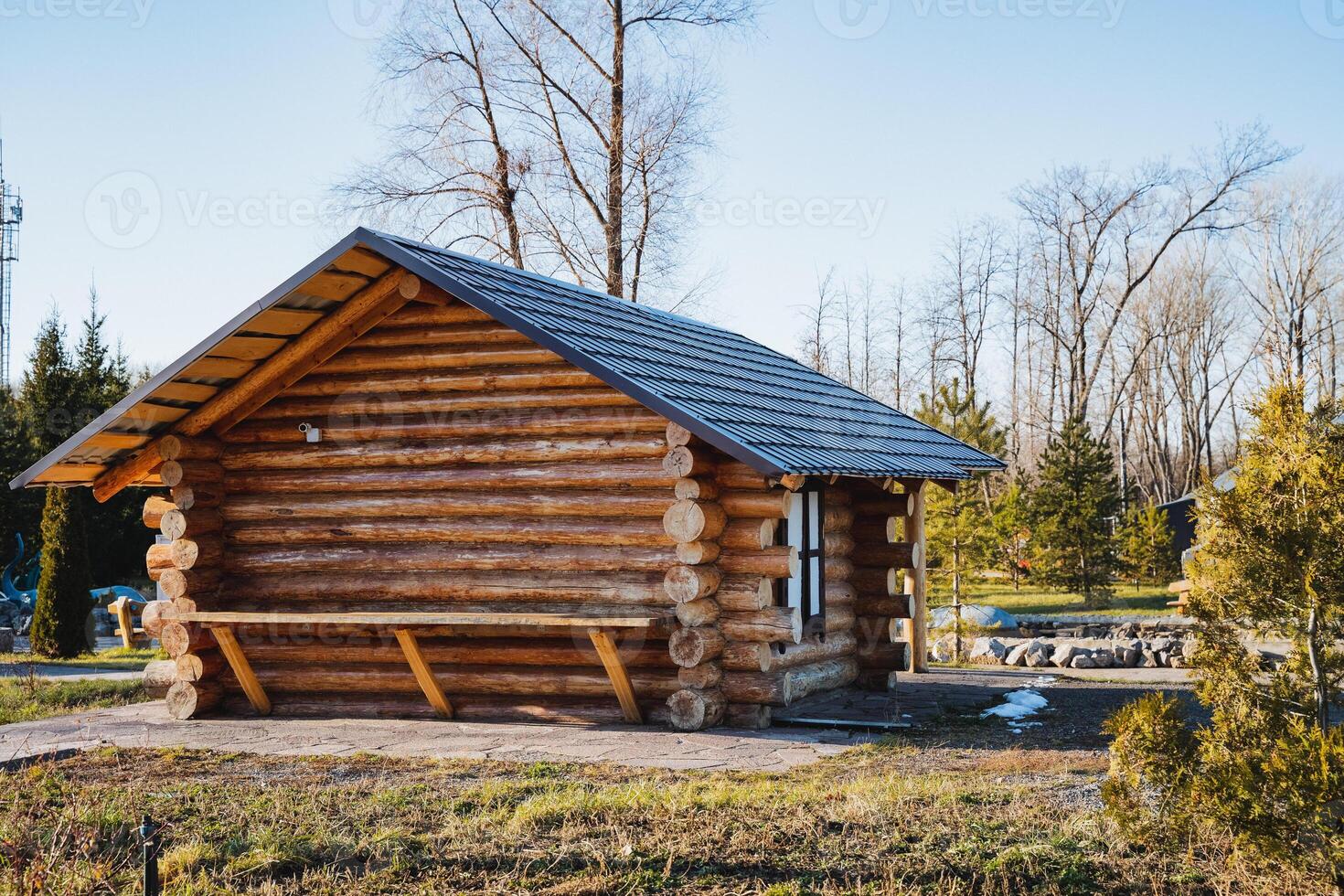 Nestled in the center of an expansive, vibrant field, a charming small log cabin featuring a sturdy slate roof stands proudly, surrounded by natures beauty and tranquility photo