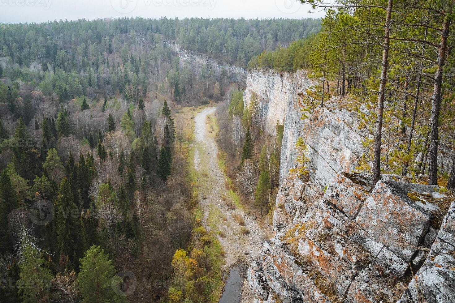 A picturesque river flows gracefully through a stunning valley that is beautifully surrounded by lush trees and rugged rocks, creating a serene and natural landscape to enjoy photo