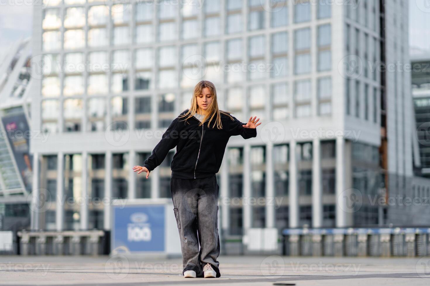 Young dancer performs on an urban plaza during a sunny afternoon in the city photo