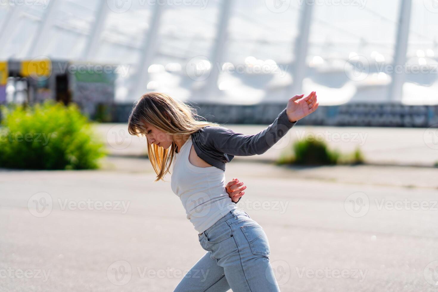 Young woman dancing joyfully on a sunny day in an outdoor setting photo