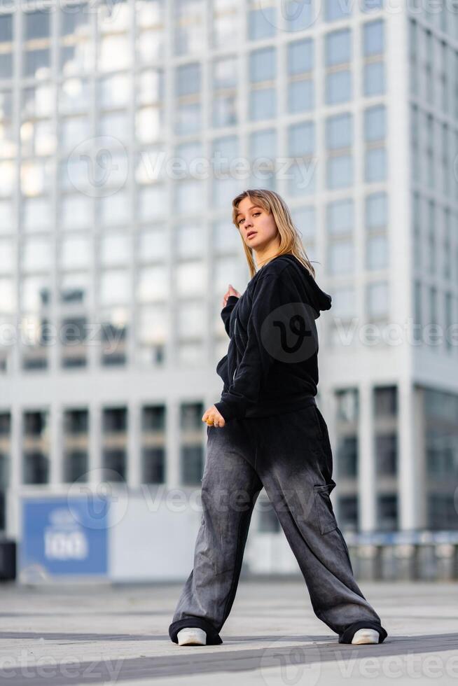 Young woman confidently posing in urban setting with modern architecture photo