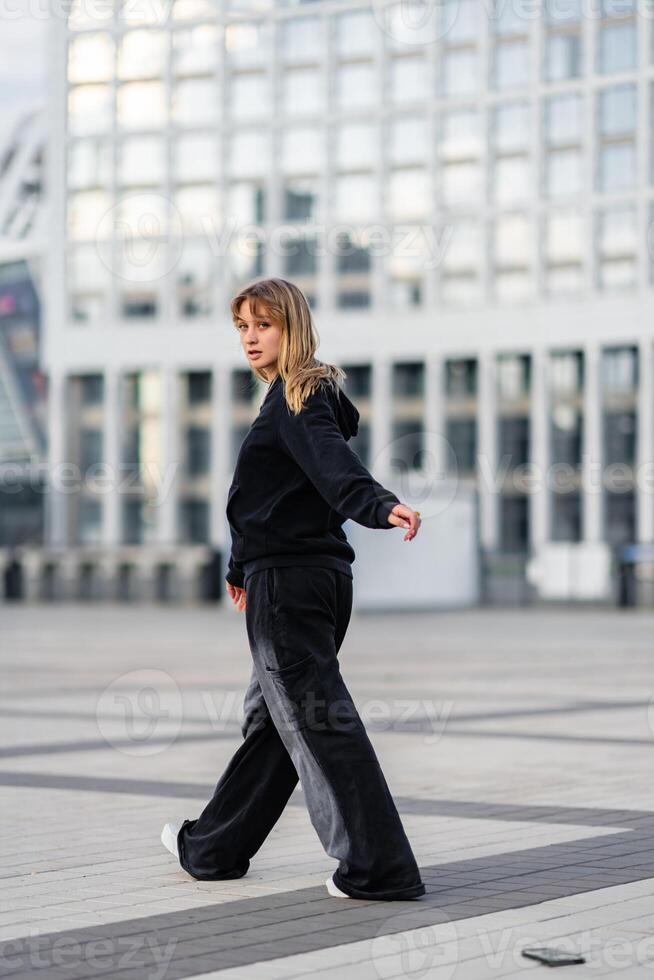 Young woman in black athletic wear walking outdoors in urban setting photo