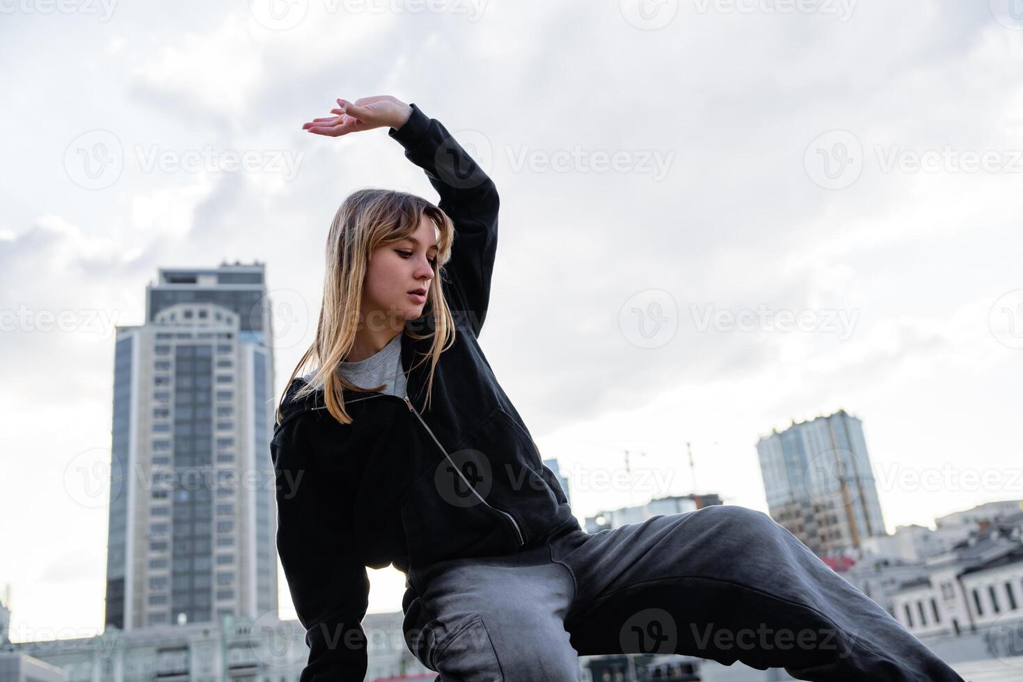 Young dancer performing a graceful movement on a rooftop in the city photo