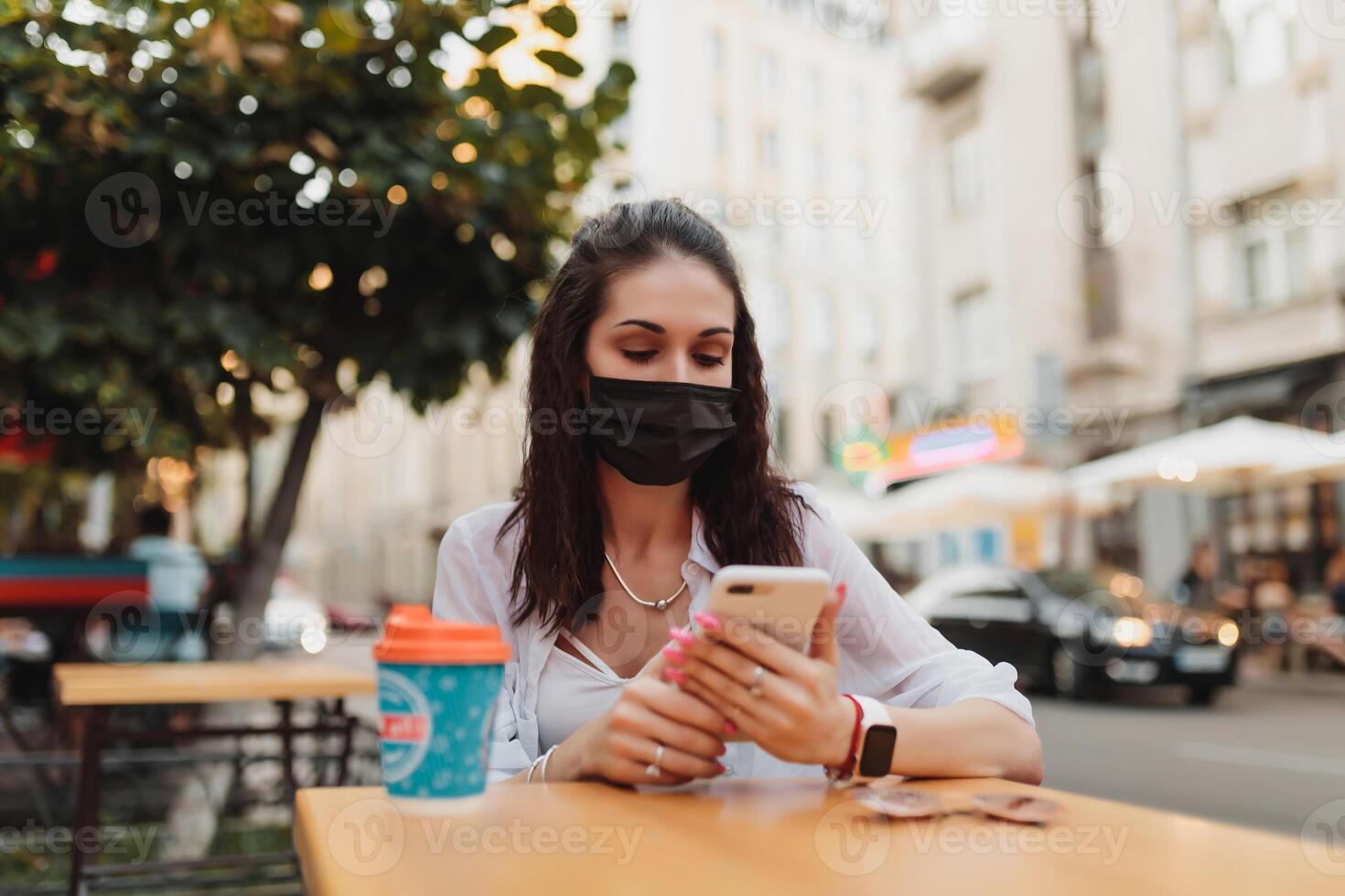 Young woman in glasses and mask uses the phone. photo
