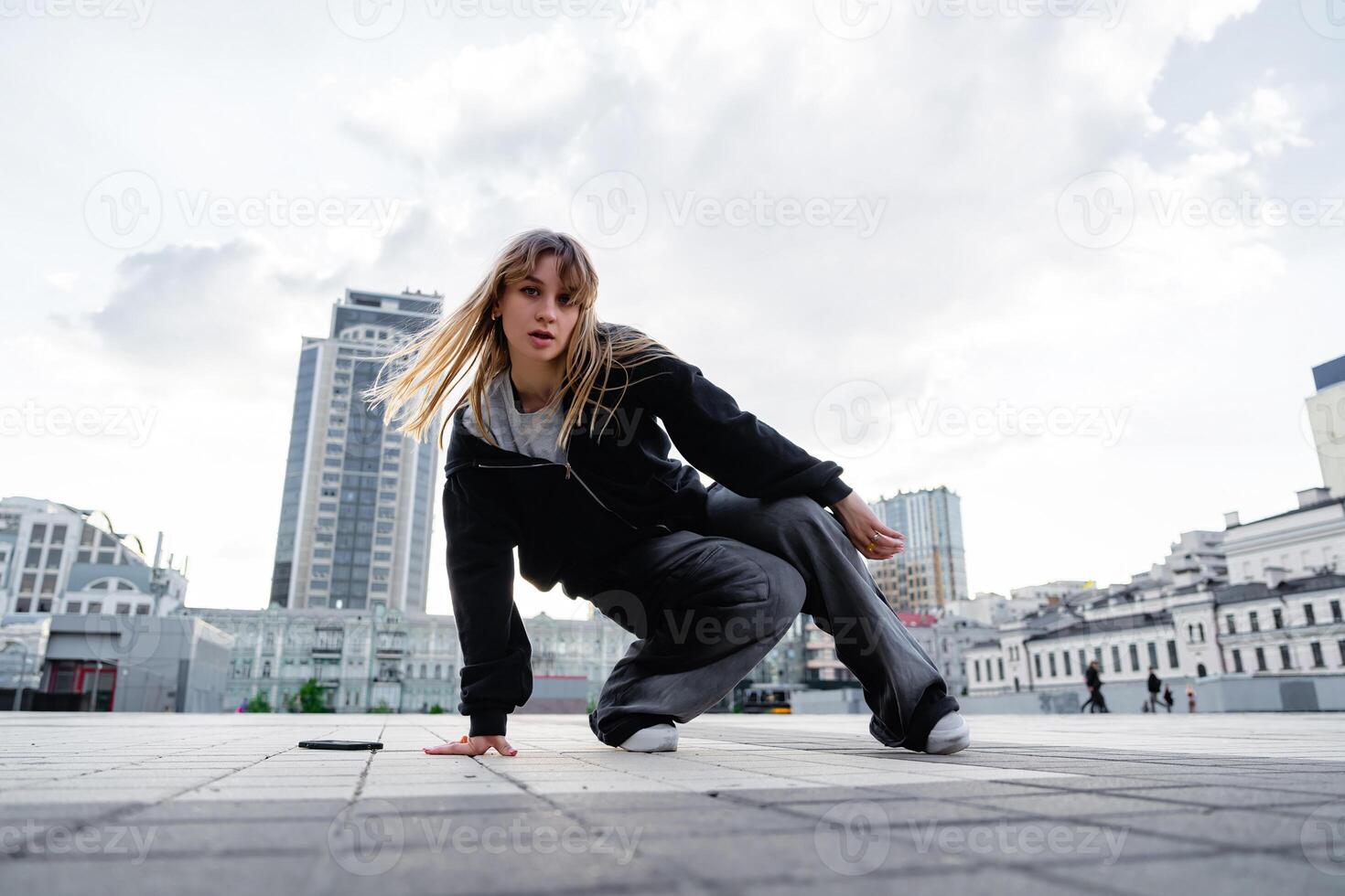 Young dancer practicing breakdancing moves on urban plaza during daytime photo