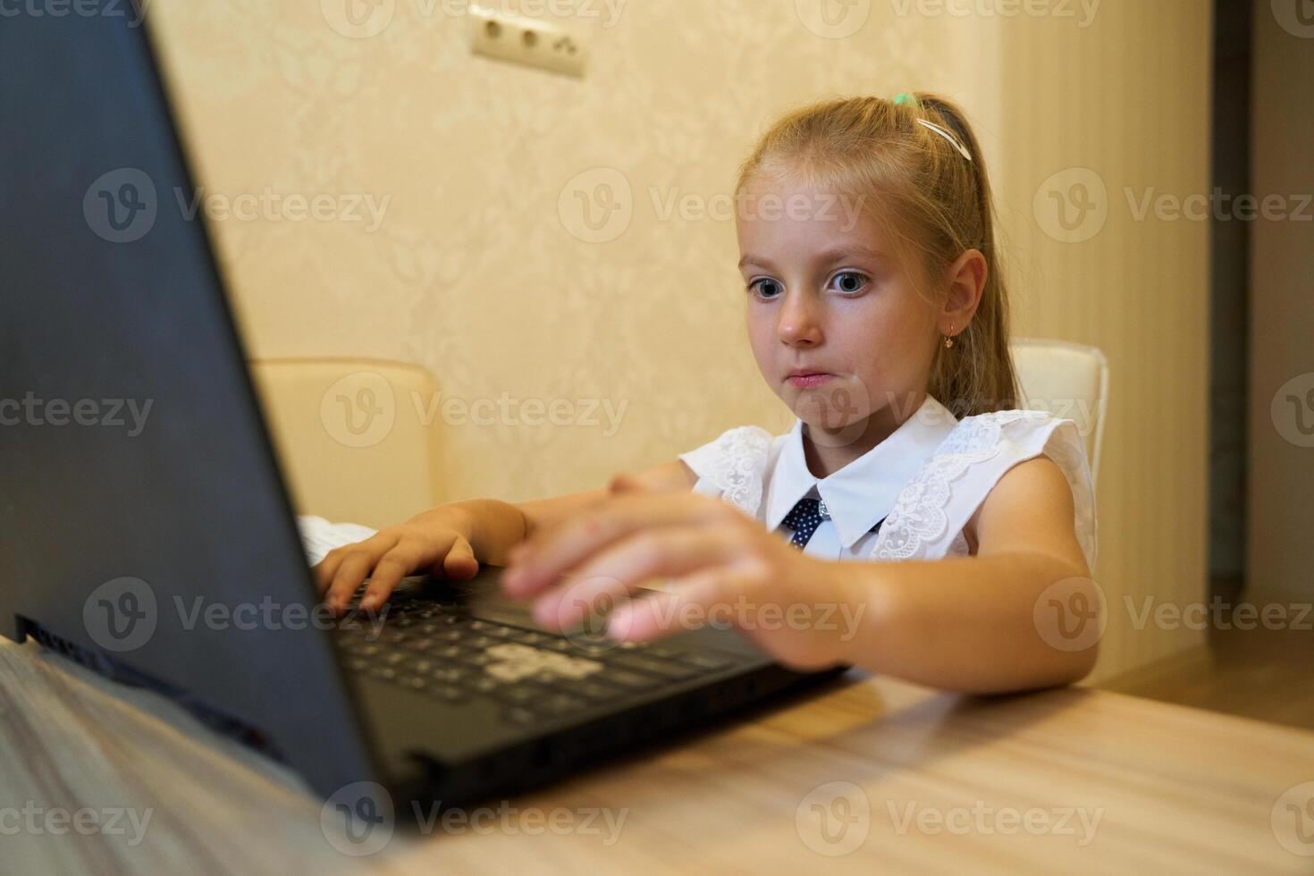 Young girl focused on laptop while studying in a cozy indoor space photo