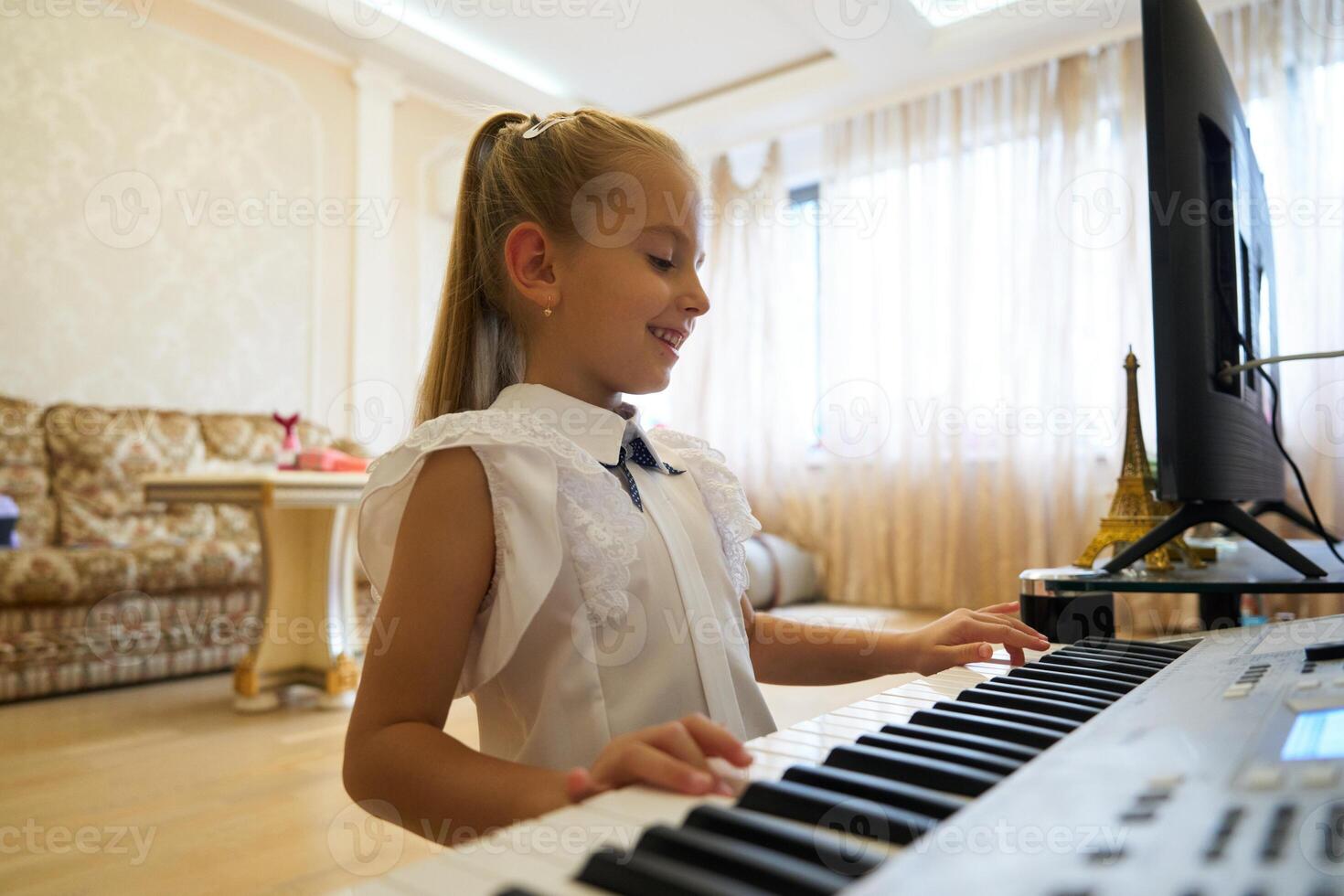Young girl enjoying music while playing keyboard in a bright living room photo