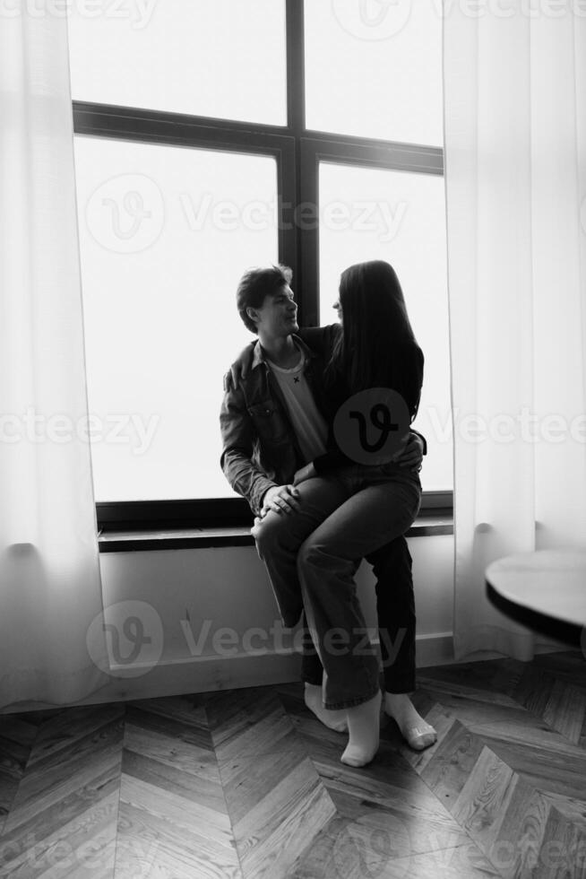 Couple enjoying a quiet moment together by a large window in a cozy setting photo