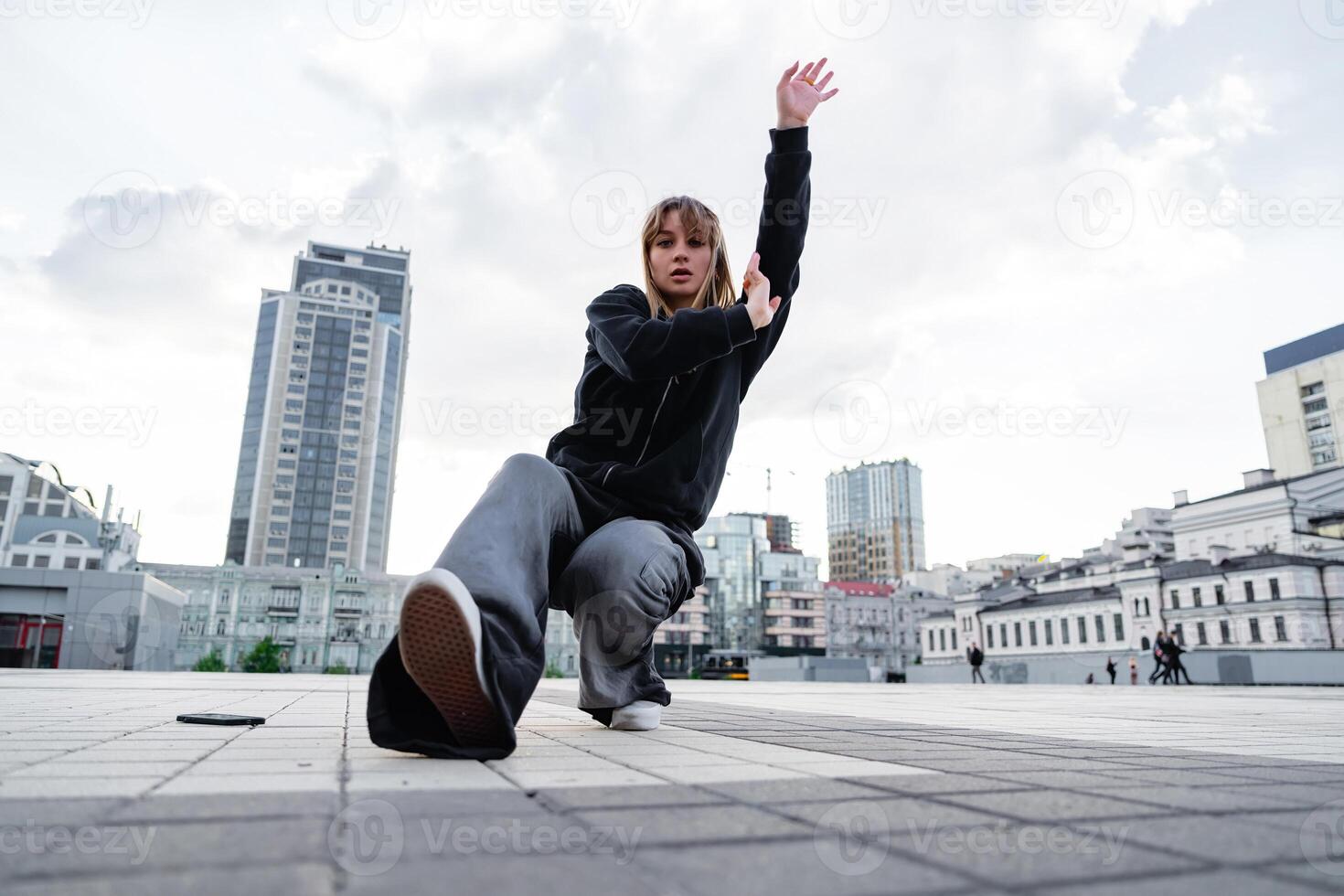 Young dancer performing a dynamic move in an urban setting during the day photo