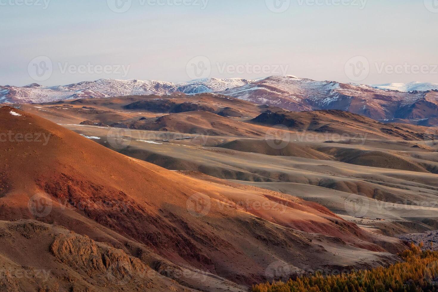 Unusual texture of the mountains, there is snow in the veins of the rock, the surface of the plateau is heated by the sun. Amazing red mountain plateau at sunset is lightly sprinkled with snow. photo