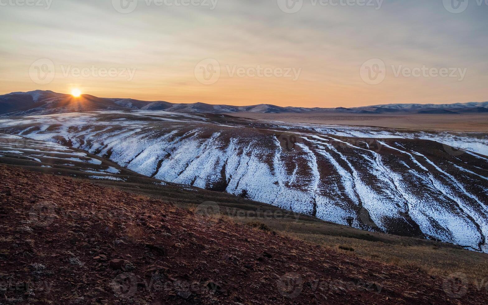 Scenic sunset mountain layers landscape with golden clouds in valley among mountains silhouettes under cloudy sky. Vivid panoramic sunset or sunrise scenery in mountain valley in illuminating color. photo