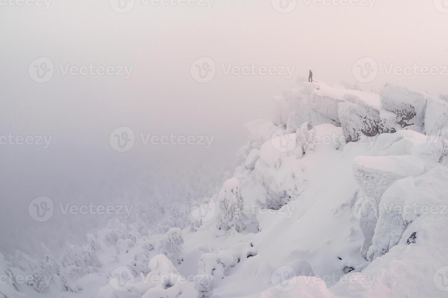 Harsh winter. Man stands on top mountain photo