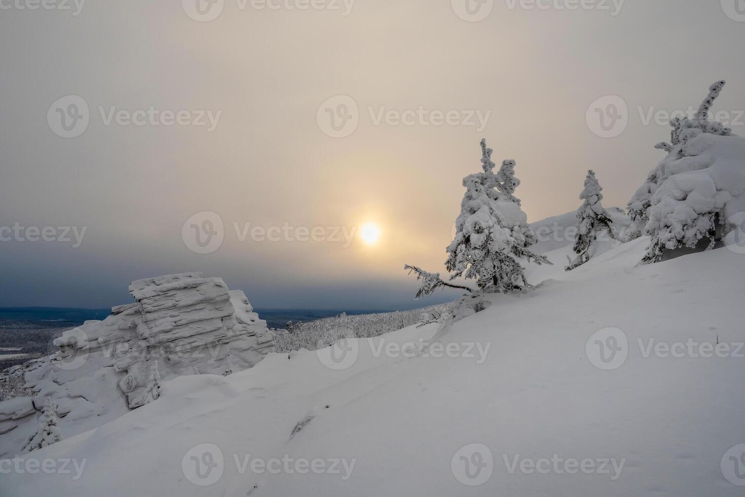 Sunset cold sun has illuminated snow covered stone hill photo
