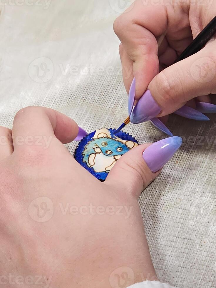 art process of pouring epoxy resin into a wooden toy. Technology process of creating a painting in style resin art, works with epoxy in studio, makes a wooden stand with the image. Close up. photo