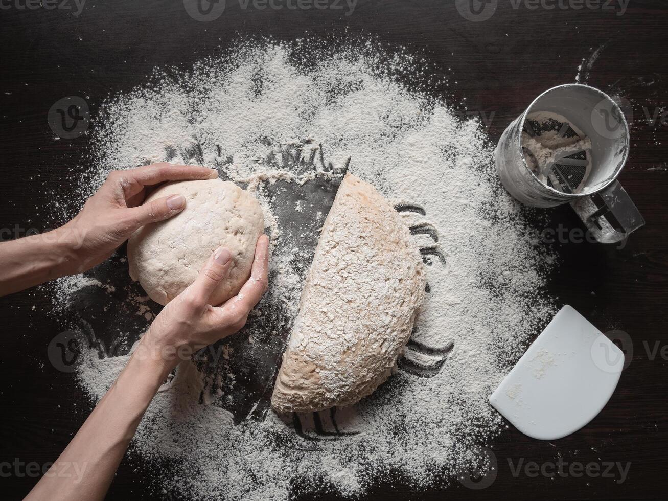 Baker's hand holds the raw yeast-free dough on a dark background. White bread texture. Mankind oldest staple foods. photo