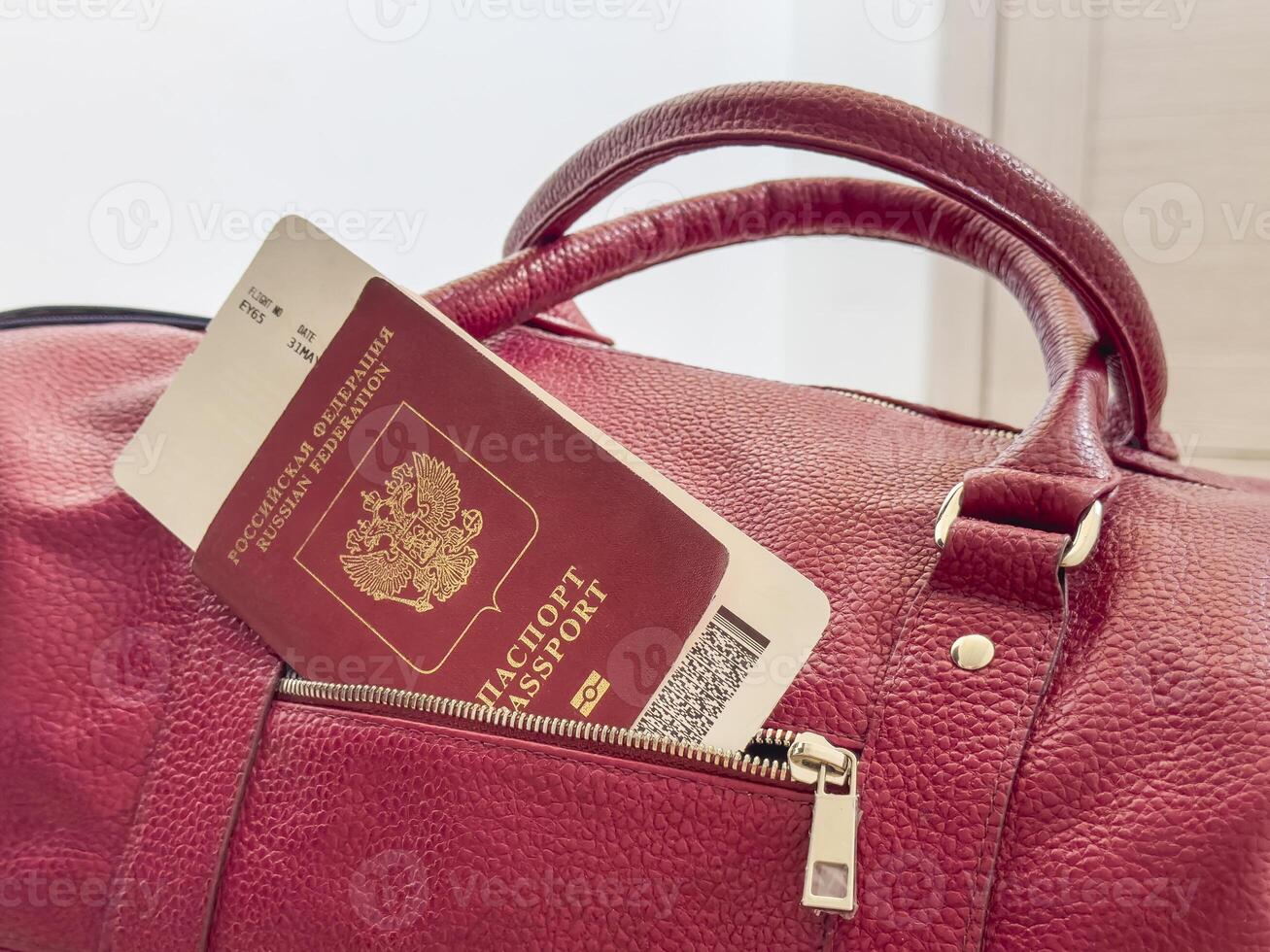 Red passport and boarding pass are sticking out of the pocket of the bag. photo