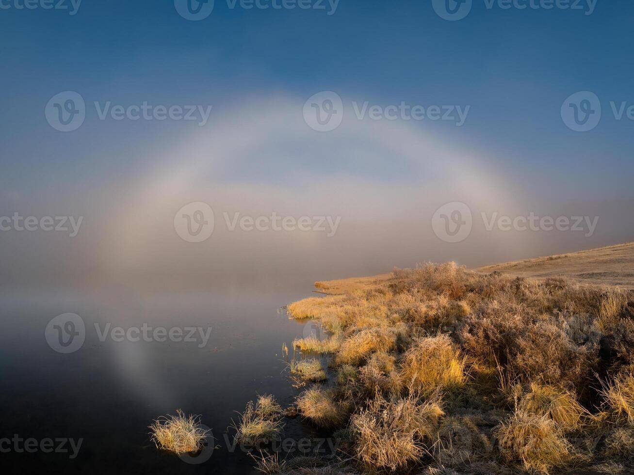 Sunny halo over an autumn lake. Amazing minimalistic autumn sunny landscape with a lake in a thick fog and a round solar halo. photo