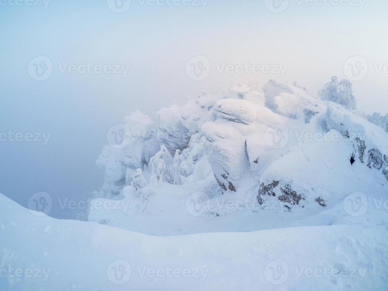 Beautiful snowy and rocky mountain landscape with frozen fog. photo