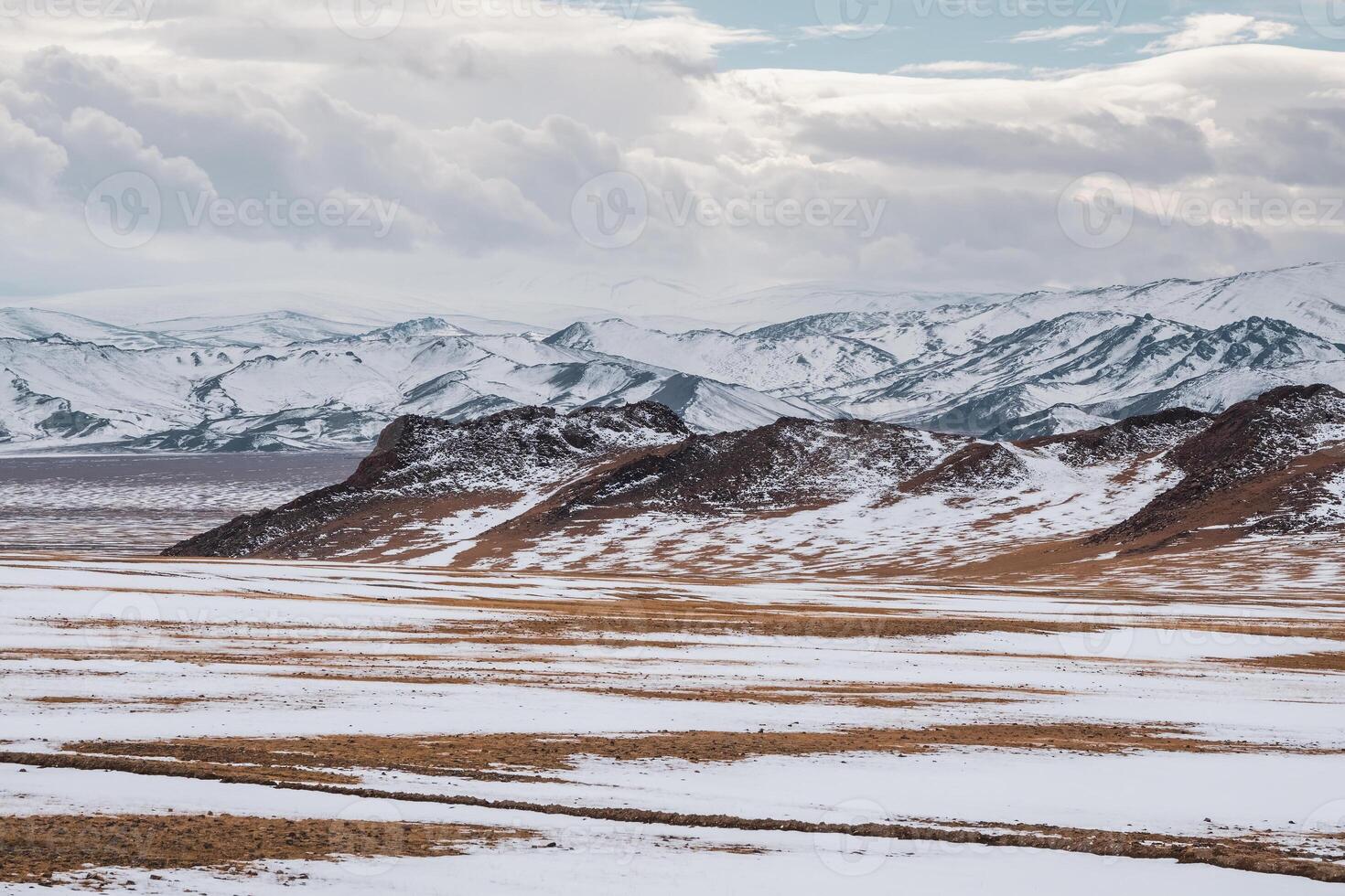 Pastel colors with the snow covered mountains in the distance. Scenic minimalist landscape with rocks in pastel tones. Snowy pasture scenery in winter. Mongolia landscapes. photo