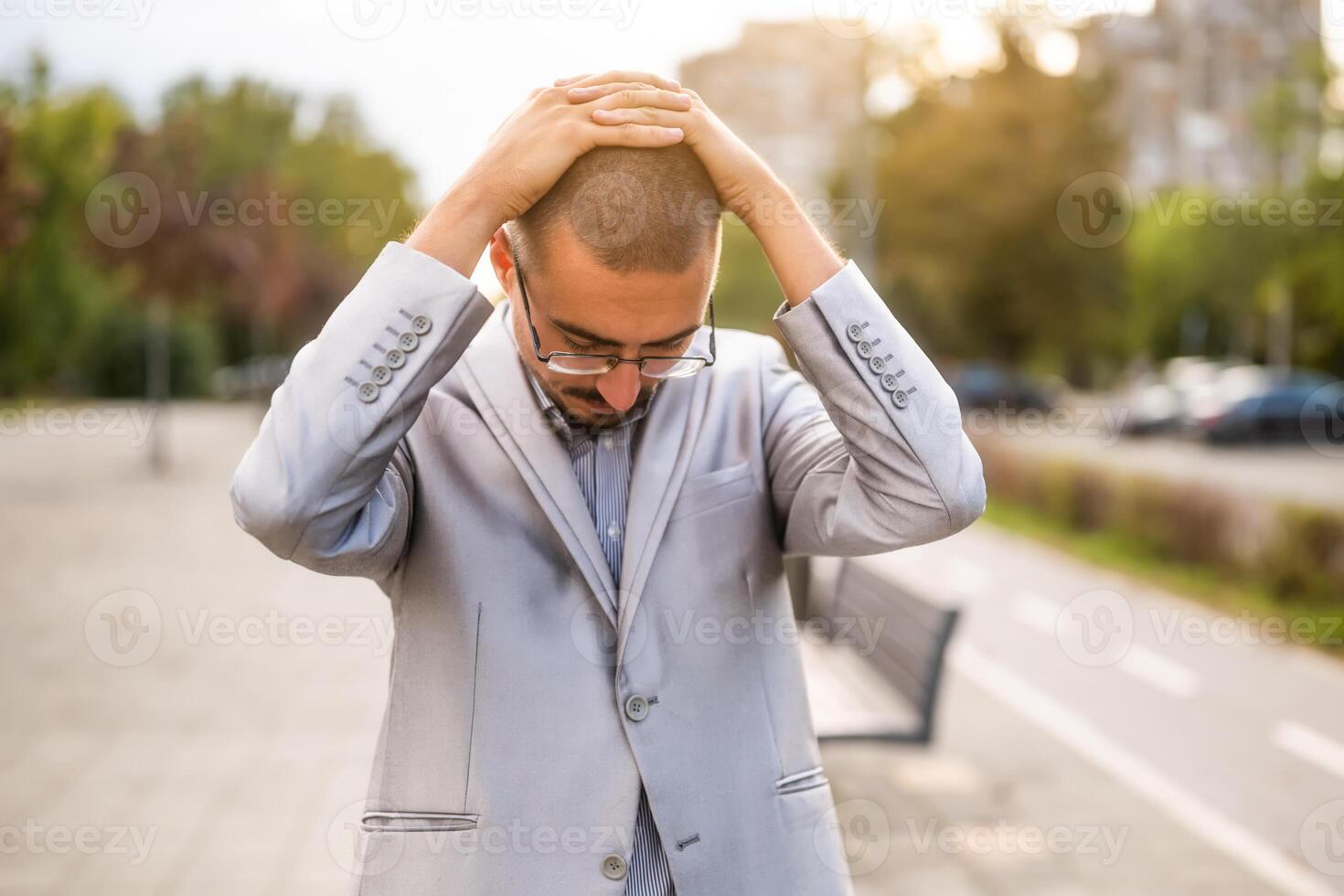 Anxious and displeased young businessman who is standing in the street. Exhausted and disappointed businessman after work. photo