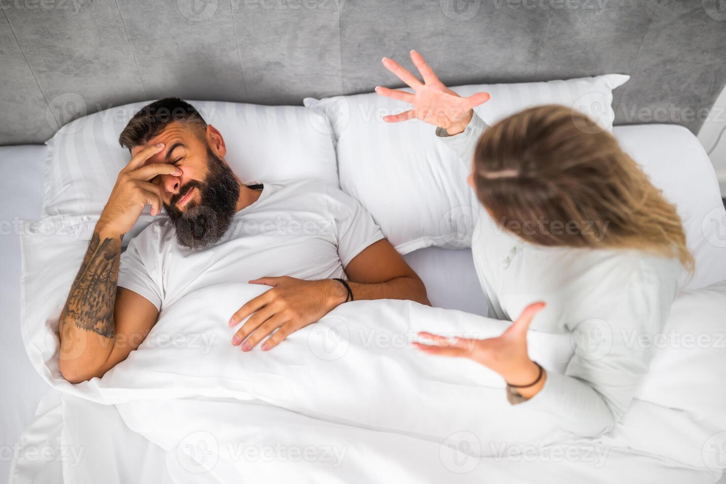 Couple is lying in bed and arguing. The woman is angry with the man. photo