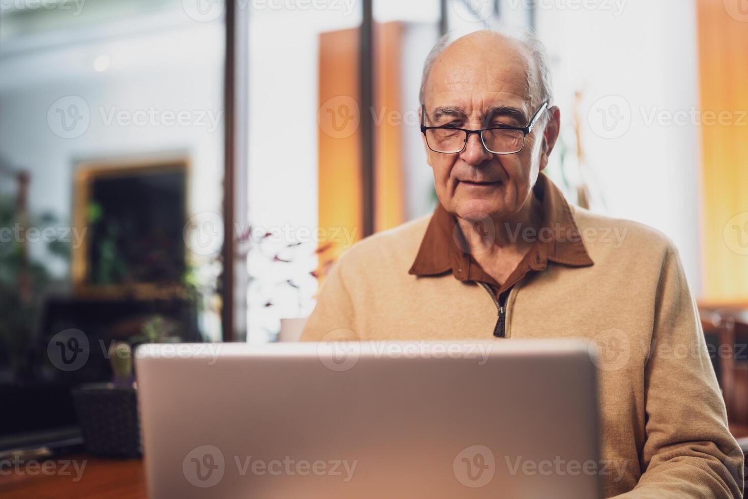 Senior man in casual clothing with eyeglasses using laptop while enjoying sitting in the city cafe. photo