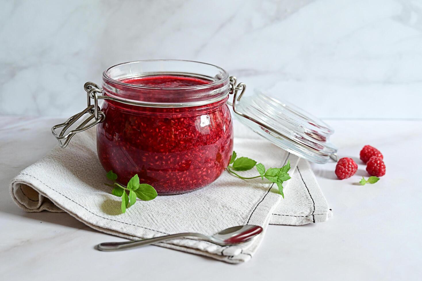 raspberry jam in a glass jar on a white background, tea with raspberries, vitamins for the body photo