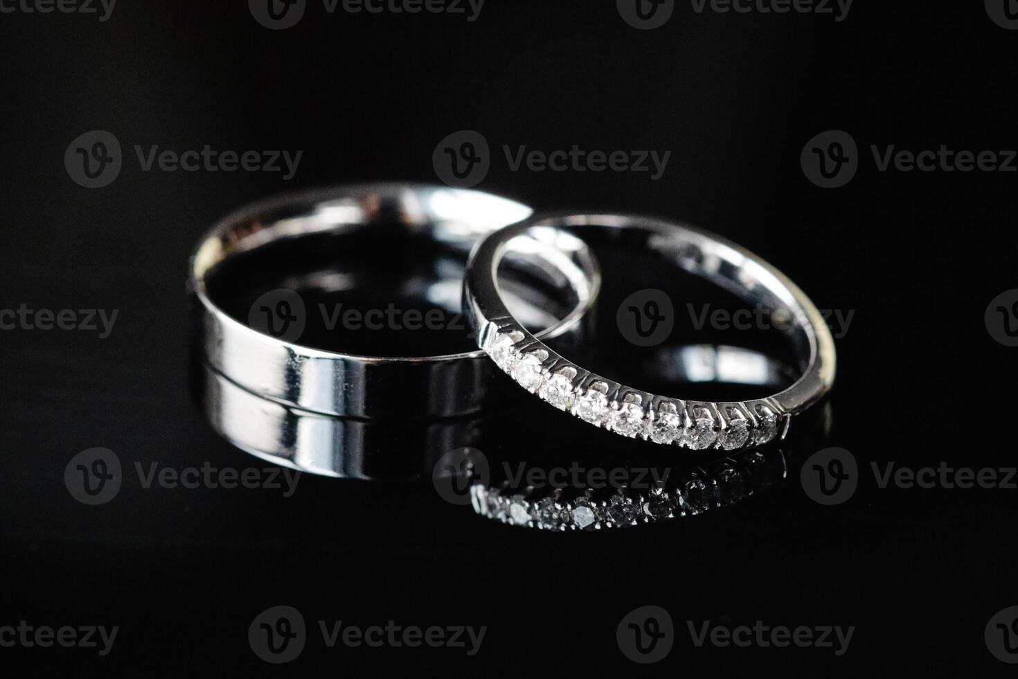 Two wedding rings showing commitment and eternal love are laying on dark background photo