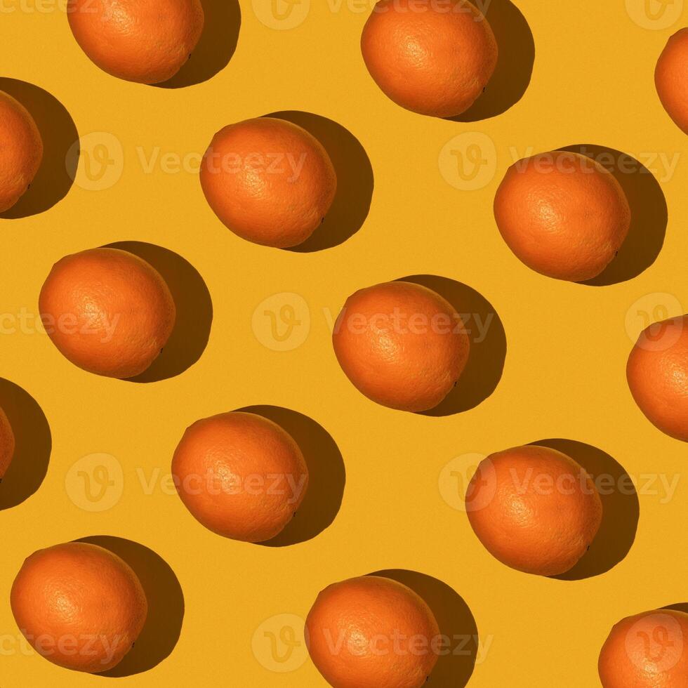 Fresh juicy whole orange on yellow background. Fruit pattern, summer concept. Flat lay Top view. Background with citrus fruits photo