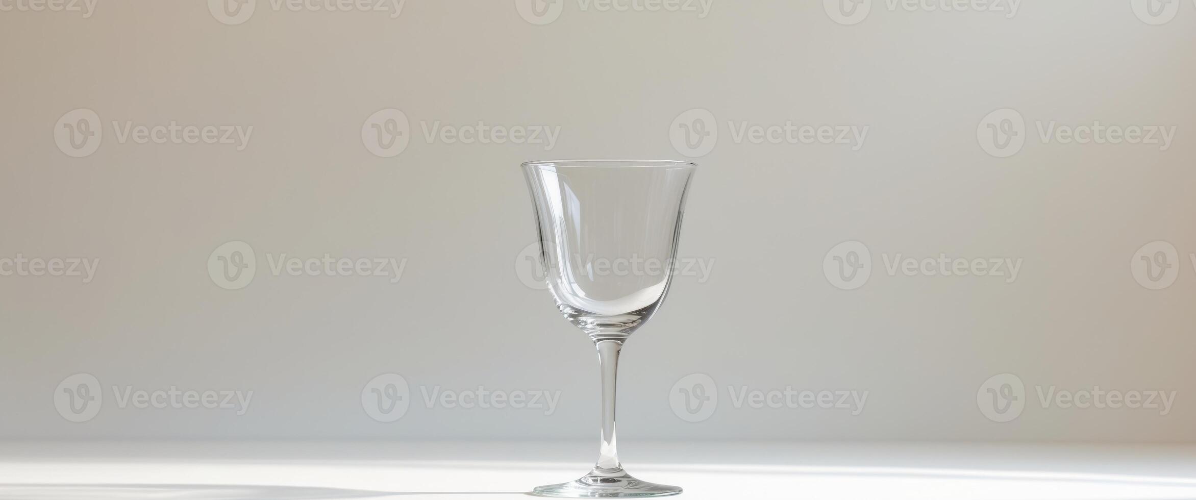 Empty stemmed glass sits on a neutral backgroundEmpty stemmed glass sits on a neutral background. photo