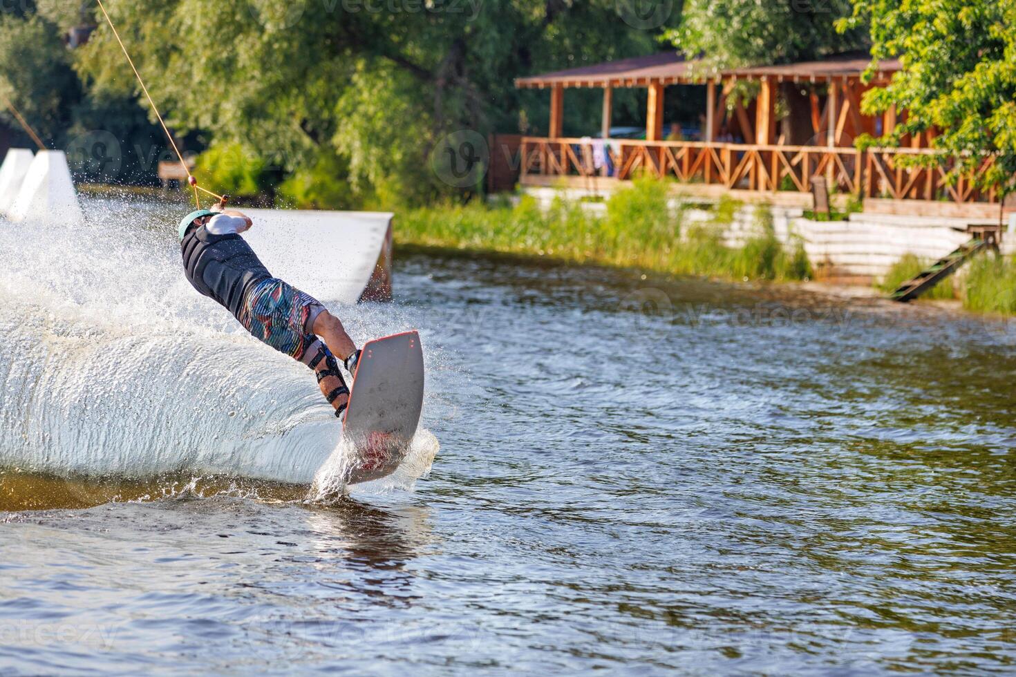 The wakeboarder makes a sharp turn over the surface of the water at high speed, creating a heap of spray behind him. photo