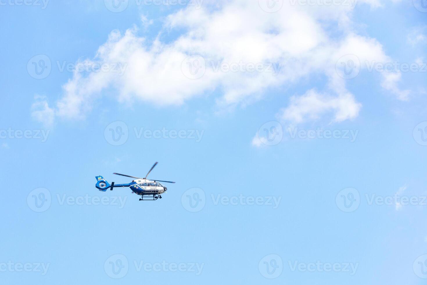 A flying police helicopter against a blue sky and a white cloud. photo