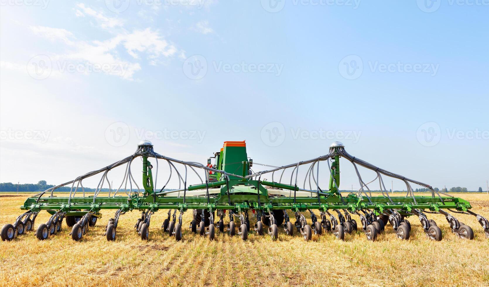 Agricultural seeder against the background of a wide field on yellow stubble and a blue cloudy sky on a summer day. photo