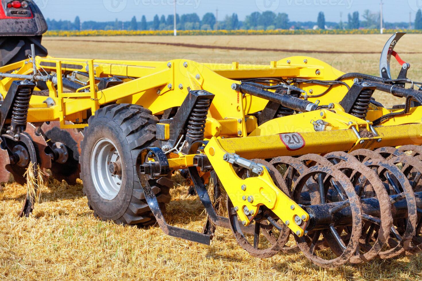Hitch of a powerful multi-row disc harrow with a tractor on the background of an agricultural field. photo