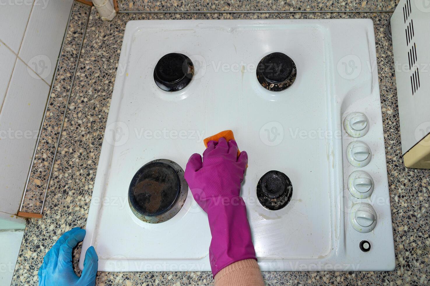 The hostess in latex gloves cleans the kitchen and washes the gas stove. photo