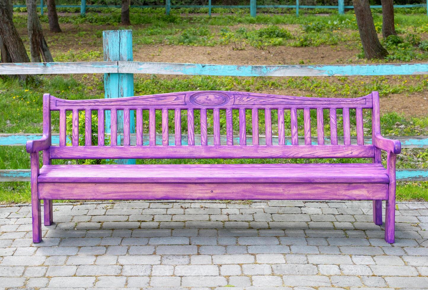A pink wooden bench on a paved paving slab against the backdrop of a spring park. photo