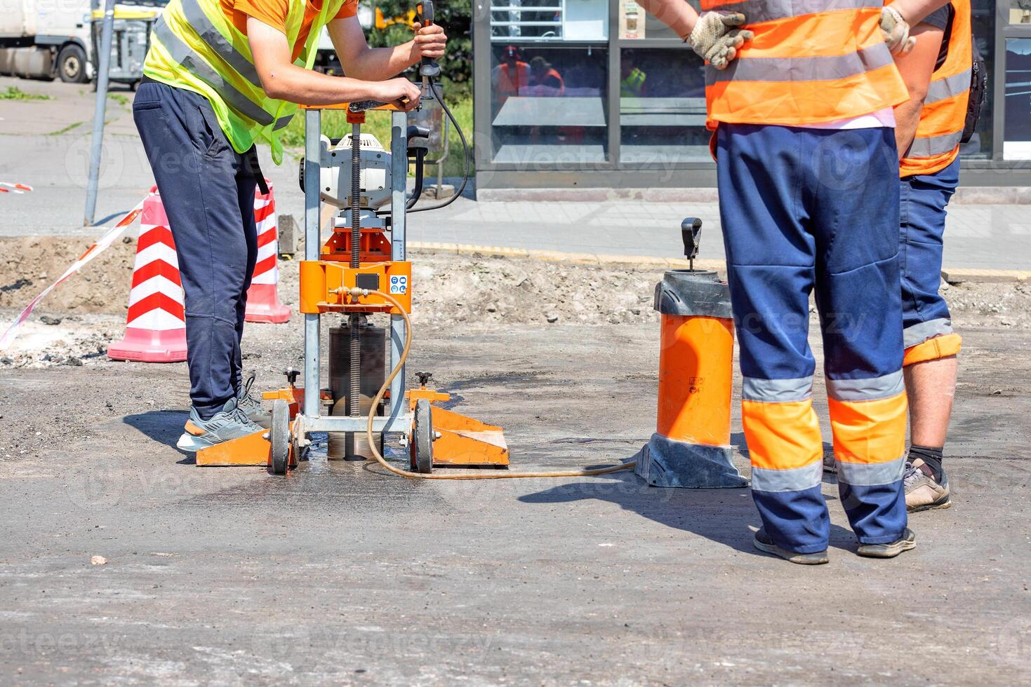 Road workers use a core drilling machine to take cores from an asphalt pavement during road repairs. photo
