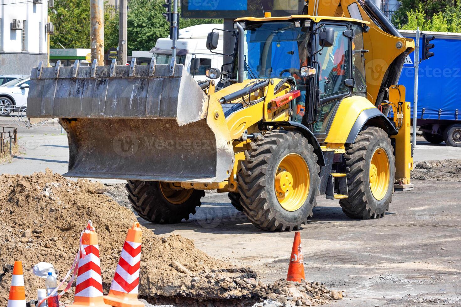 Construction tractor with a hydraulic sliding bucket on a repaired section of the road on a sunny day. photo