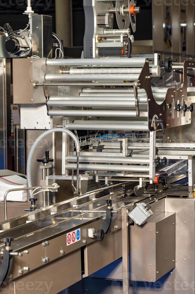 Fragment of an automatic packaging line with roller guides at a food factory. photo