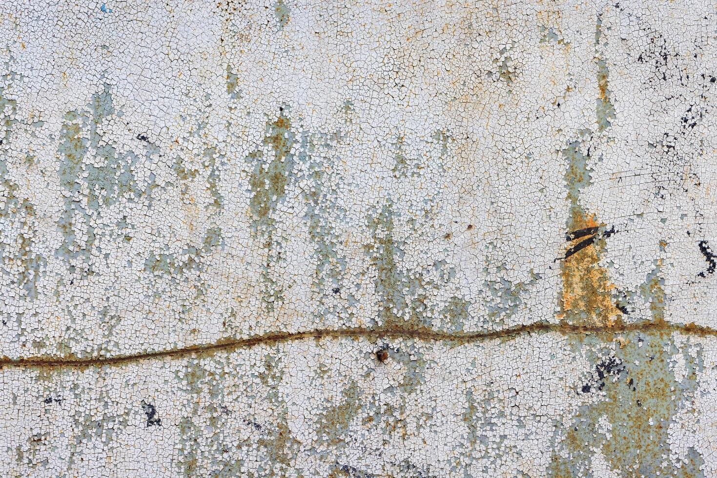 Old metal sheet with cracked paint and a rusty traced curve. photo