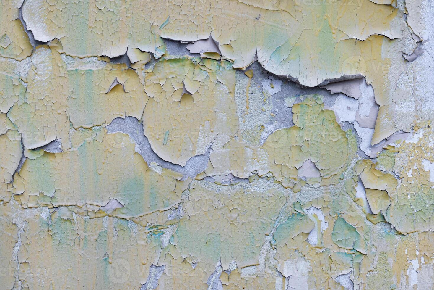 Old paint peeling off in large chunks on a concrete wall. photo