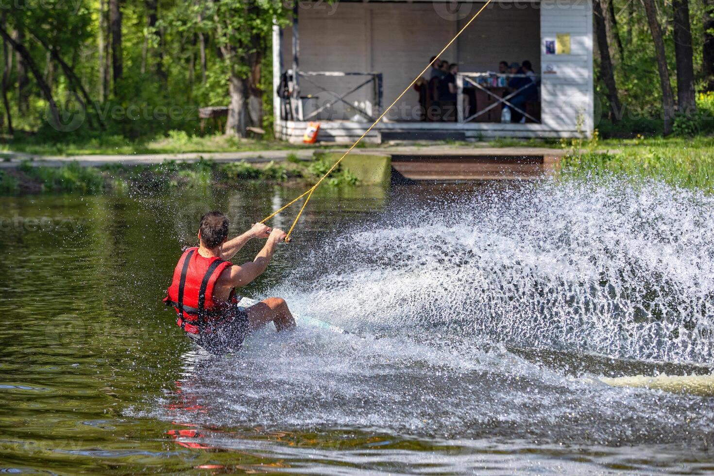 Water sport, wakeboarder rides on a water board on a warm spring day, raising beautiful large water splashes. photo