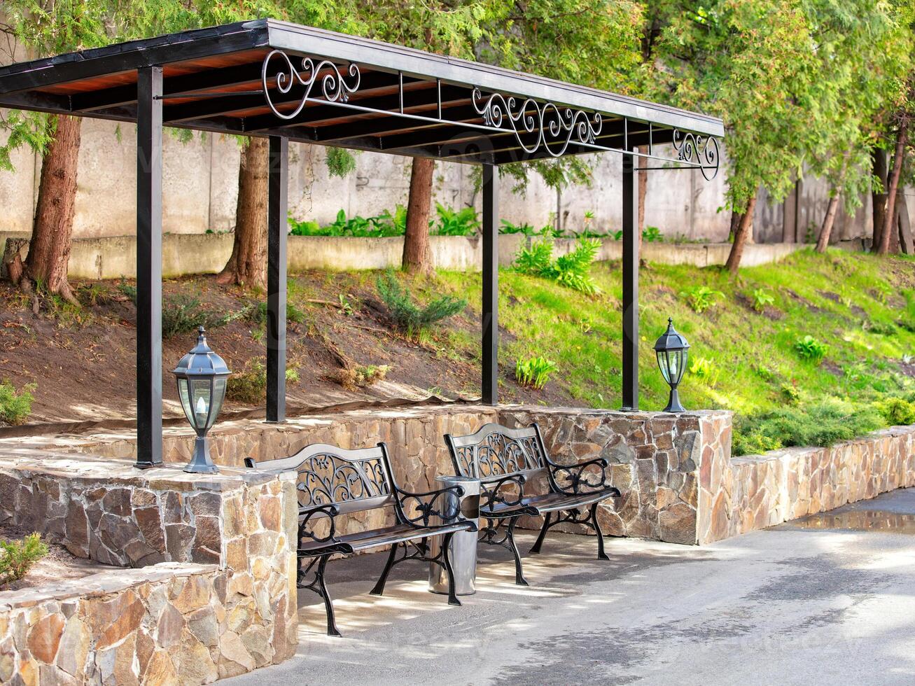 Elegant benches under a stylish canopy in a serene park setting during midday photo