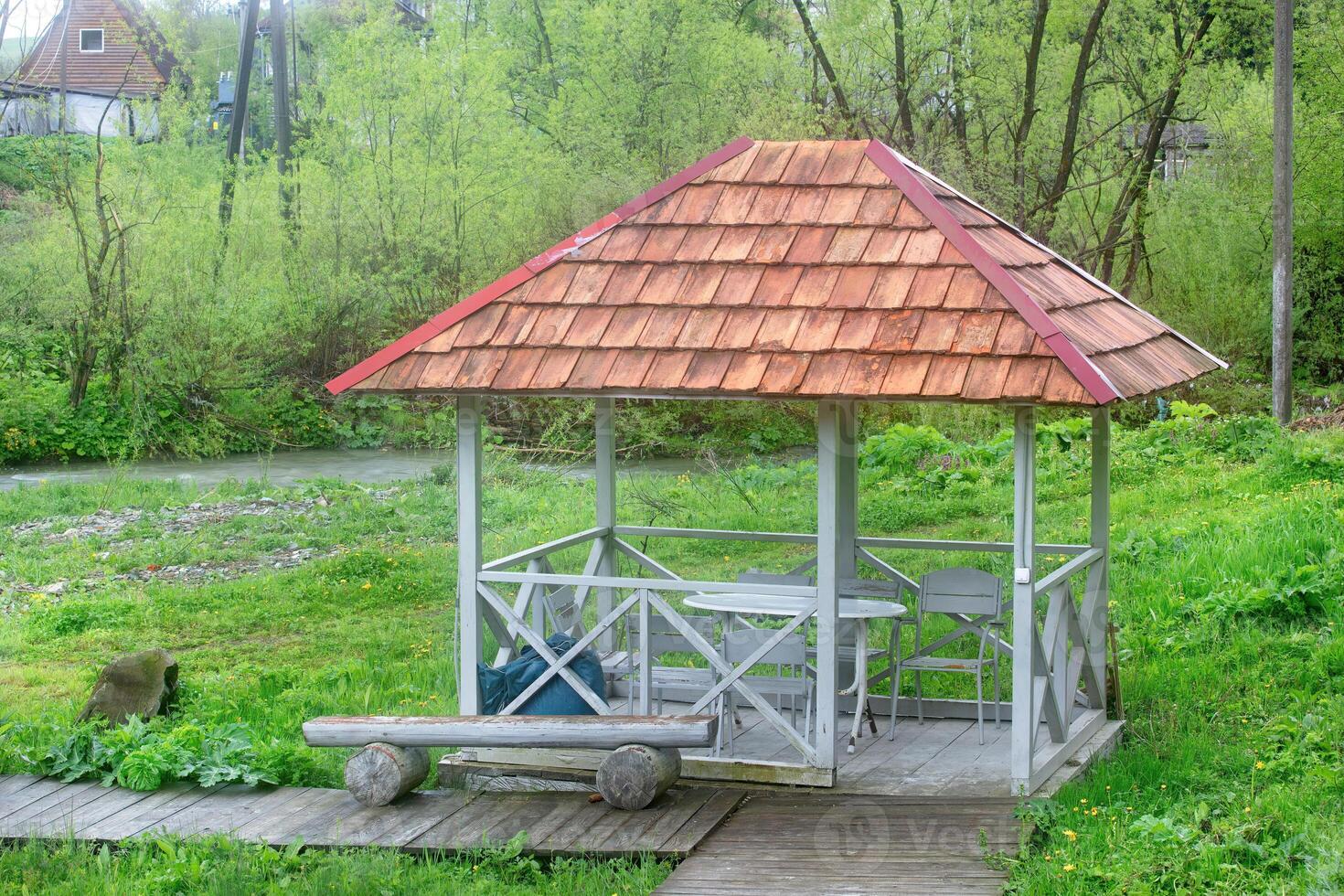 Charming riverside gazebo surrounded by lush greenery in a tranquil setting photo