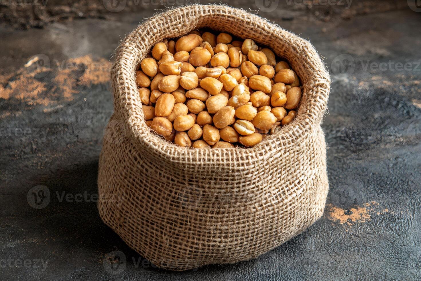 Roasted peanuts filling a burlap sack on a dark background photo