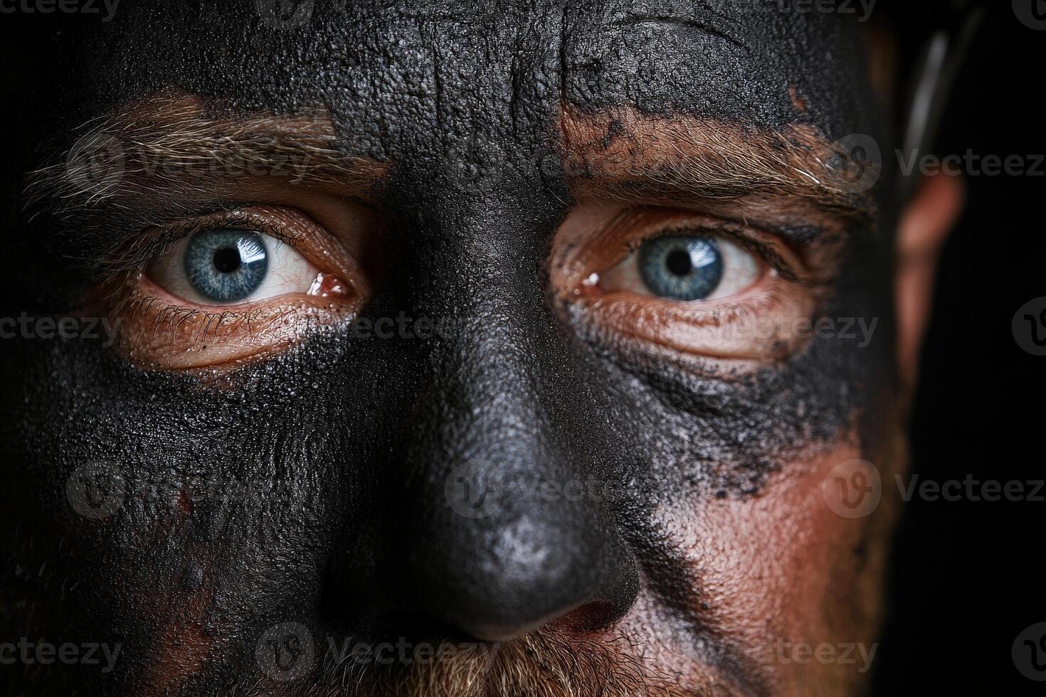 Miner with coal dust face gazes intensely into the camera during work photo
