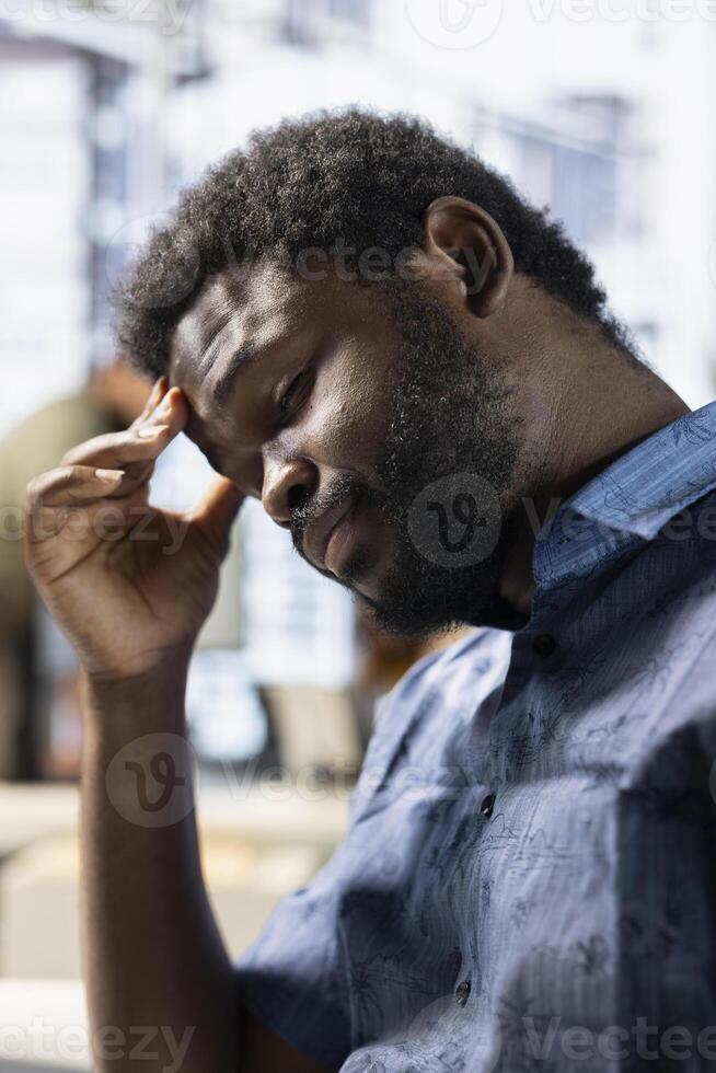 Exhausted employee rubbing forehead while analyzing datasets on computer, checking accounting figures. Tired worker suffering headache from overworking, solving tasks for team project photo