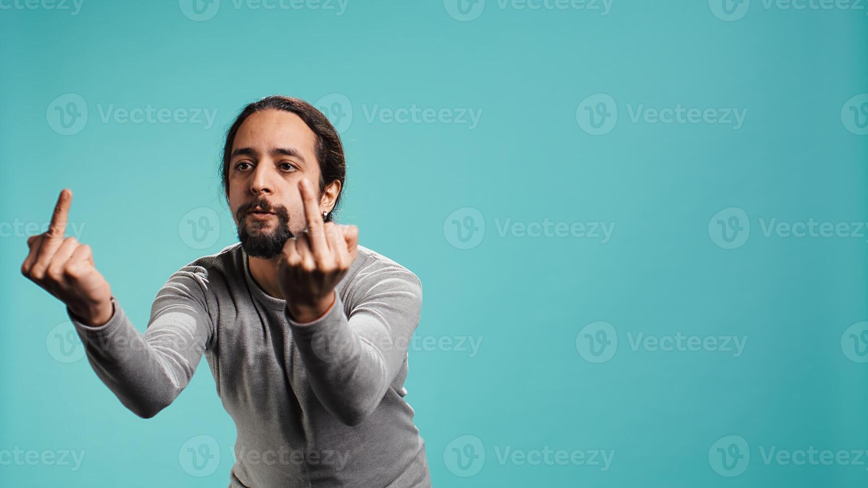 Irked man fighting with friend, doing middle finger sign gesturing, isolated over studio background. Outraged person arguing during conversation, doing obscene hand gestures, camera B photo