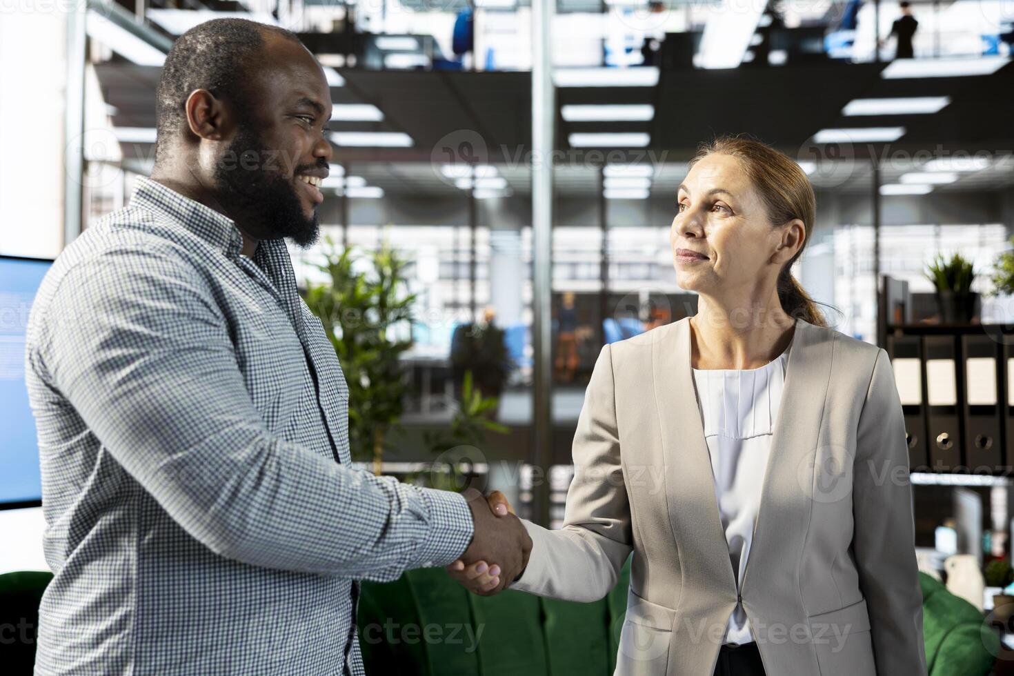 Smiling businessman doing handshake with client in financial startup company, making deal. Upbeat man in office shaking hand of customer after agreeing terms, having discussion photo