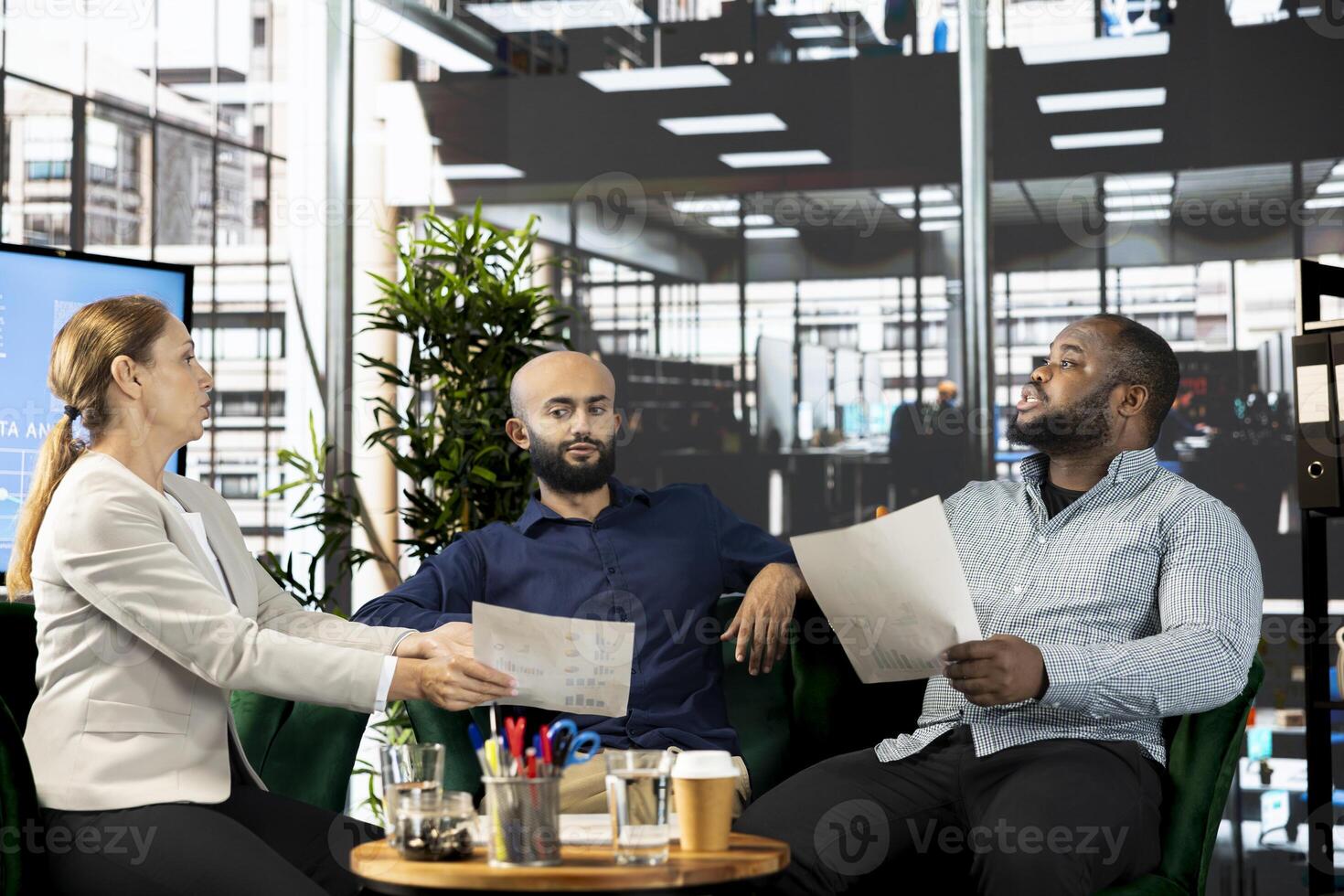 Diverse businesspeople in startup workplace looking through financial business documents. Workers in office checking accounting figures, finishing tedious paperwork, discussing about data photo